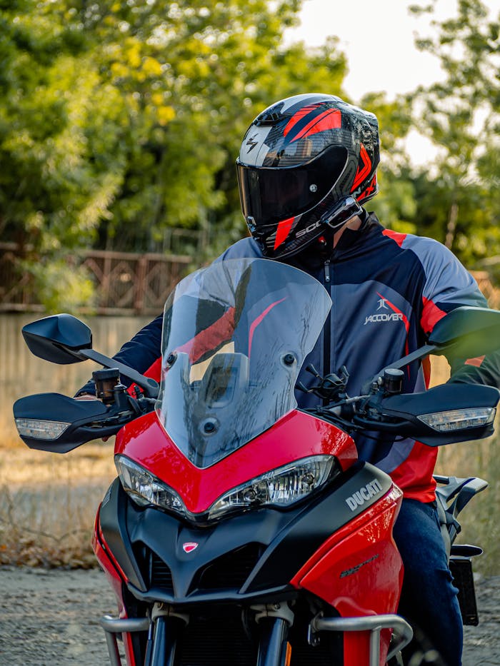 A rider wearing a helmet and motorcycle jersey on a Ducati Multistrada in an outdoor setting.